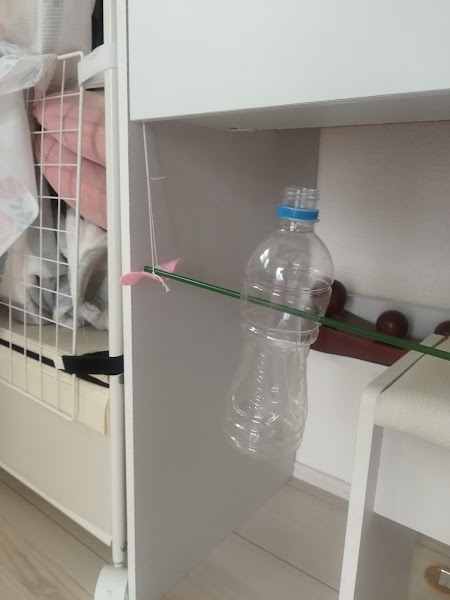手作り知育おもちゃのペットボトルが棒に通され、机の側面に設置された様子（犬用）