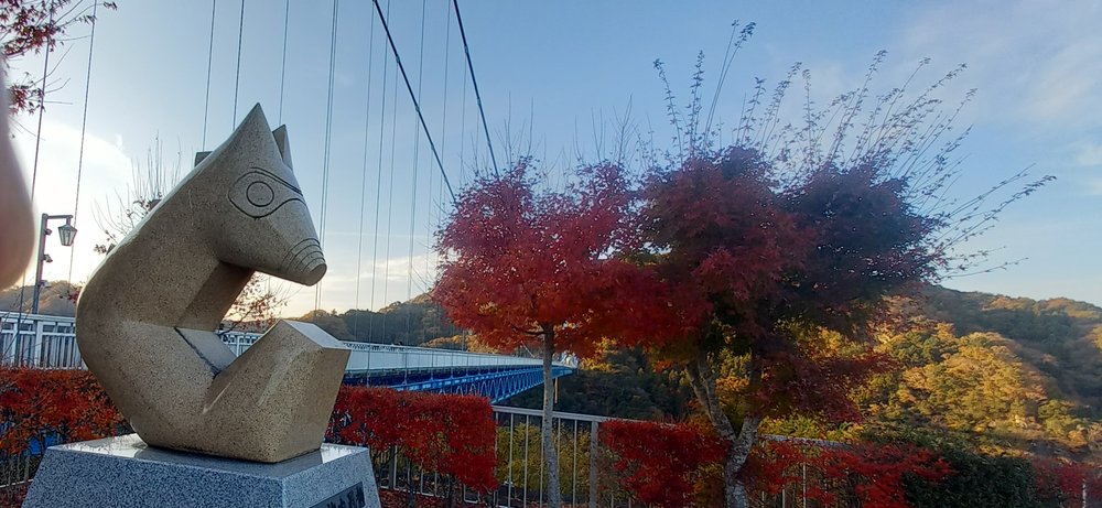橋のたもとの像と真っ赤な紅葉